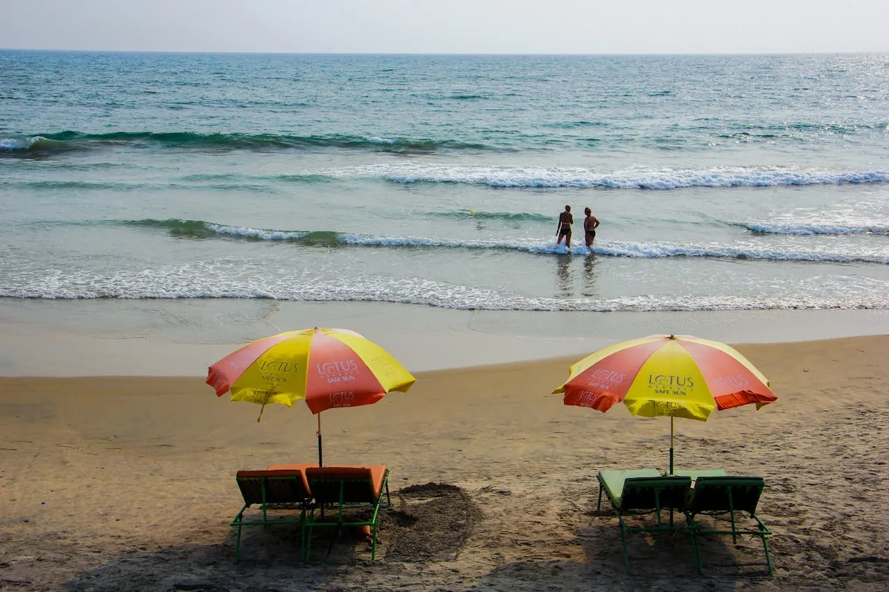 Two people on a beach under a bright sky