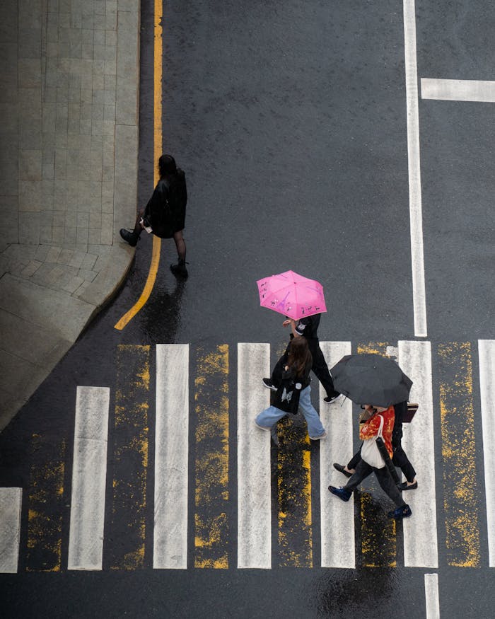 High-angle view of pedestrians with umbrellas crossing a rain-soaked intersection in Moscow.